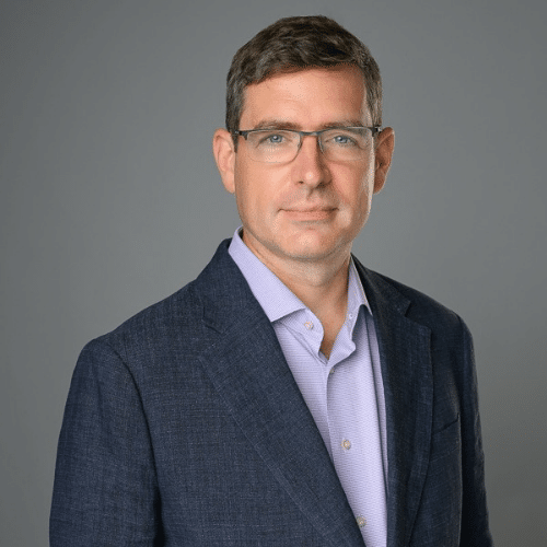 Man with glasses smiling on grey backdrop